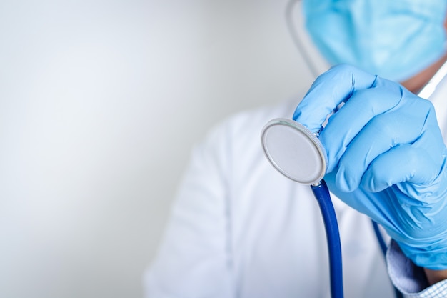 Médicos usando máscaras e luvas azuis. Segure um estetoscópio para examinar o paciente. Conceito de serviço de assistência médica, cura o coronavírus. copie o espaço