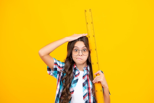 Medida de crecimiento de la medida de la altura del niño Cara divertida Niña de la escuela sosteniendo la medida para la lección de geometría