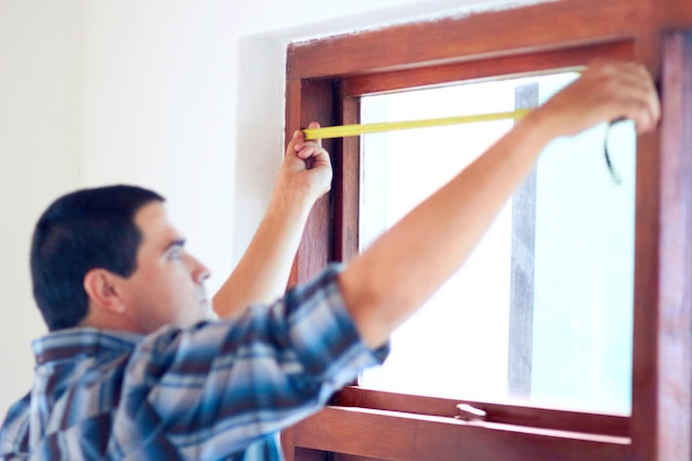 Foto la medida exacta disparo de un hombre práctico de mediana edad midiendo una ventana