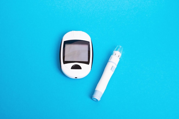 Medidor de glucosa en sangre y dispositivo de lanceta con fondo azul.