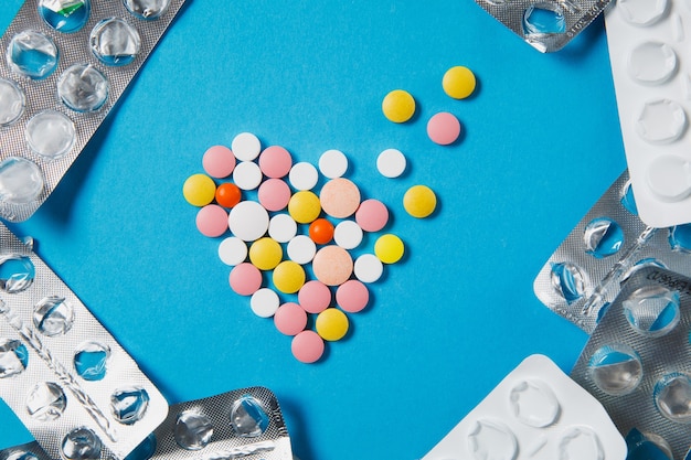 Medikamente bunte runde Tabletten in Form von Diffusionsherzen auf blauem Hintergrund isoliert