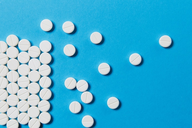 Medikamente weiße runde Tabletten angeordnet abstrakt auf blauem Hintergrund isoliert