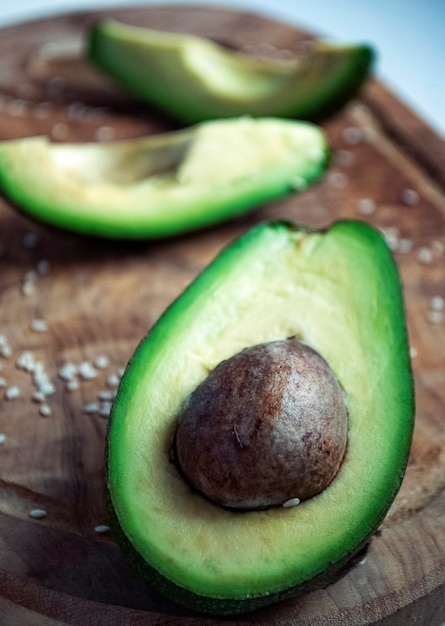 Medio aguacate con aguacate cortado en rodajas sobre una tabla de cortar.