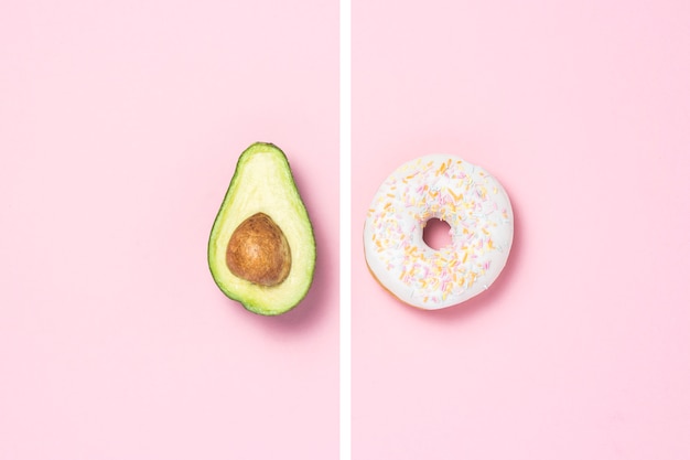 Medio aguacate y donut sobre un fondo rosa. Concepto de opciones de alimentos.