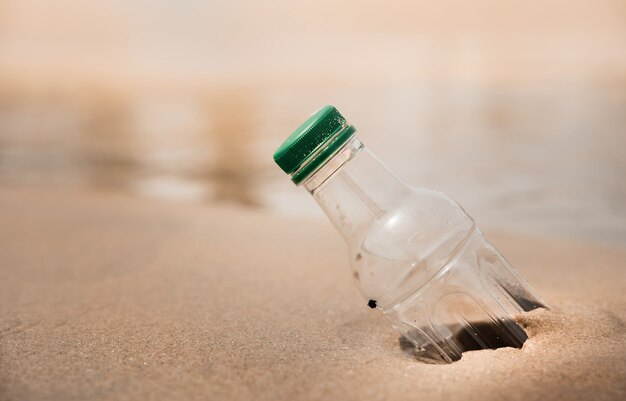 Medio ambiente, cuidado de la ecología, concepto renovable. Desechos de botellas de plástico en la arena de la playa o junto al río