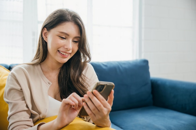 En medio de la comodidad del hogar, una mujer en un sofá escribe un mensaje en su teléfono abrazando la comunicación exitosa con una cara sonriente disfruta de la tecnología y la relajación.