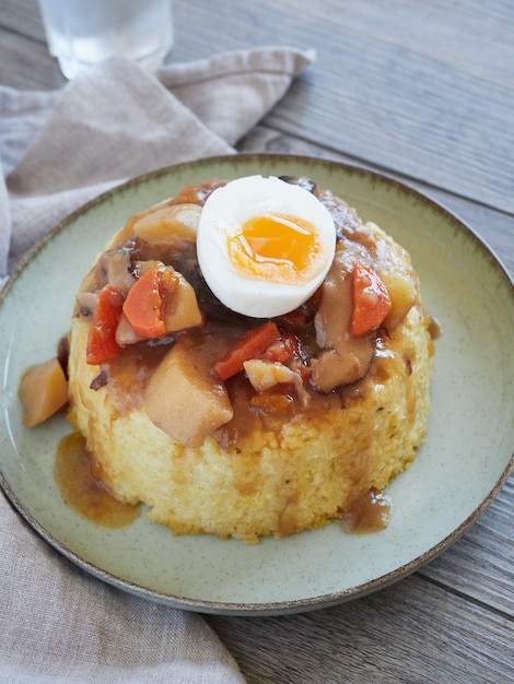 Medio guiso de huevo escalfado, champiñones y verduras sobre pastel de mijo