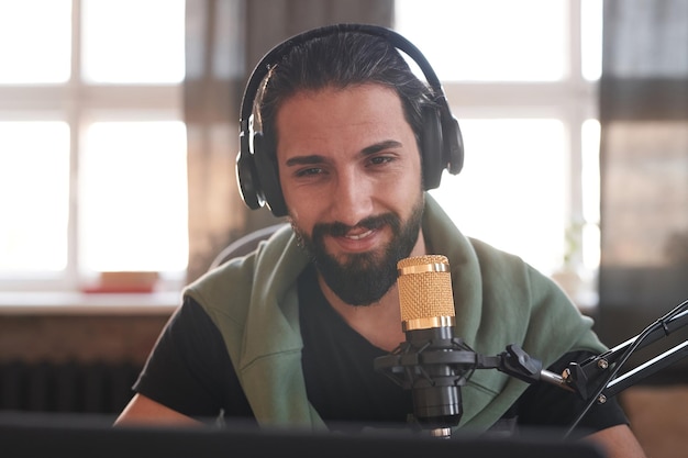 Foto medio horizontal primer plano retrato de blogger macho adulto joven feliz con barba en la cara con cabeza