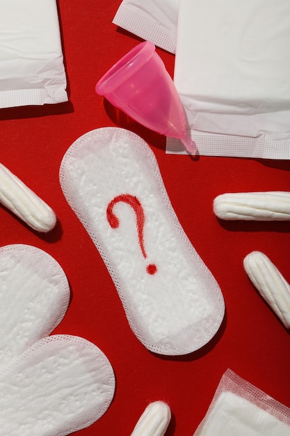 Medios de higiene femenina durante la menstruación en un fondo rojo.