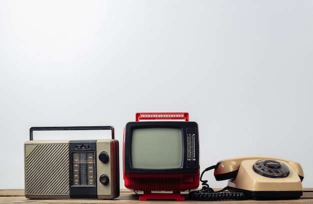 Medios retro. Viejo televisor portátil, teléfono de disco, receptor de radio sobre un fondo blanco.