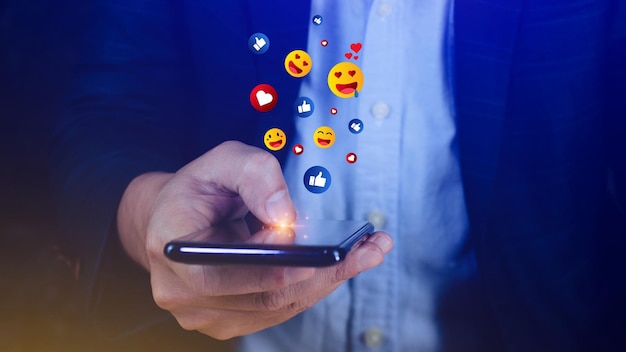 Medios sociales y concepto digital en línea Empresario que usa un teléfono inteligente que envía emojis con los medios sociales