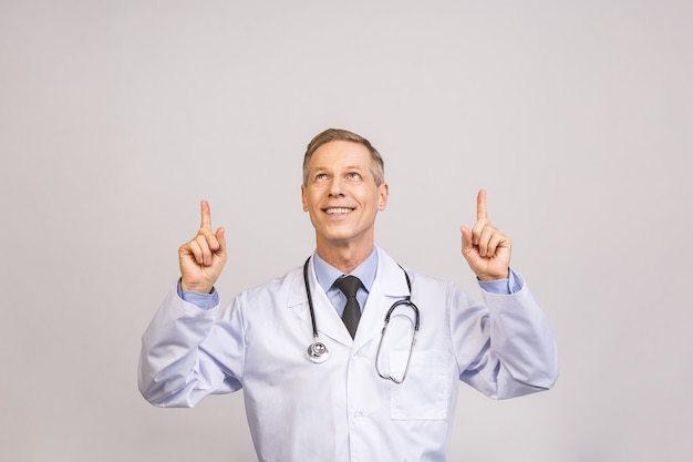 Medique o homem superior, profissional médico que aponta acima do lado com o dedo isolado sobre a parede cinzenta.