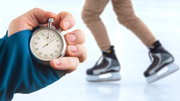 Medir la velocidad en patines con una mano de cronómetro con un cronómetro en el fondo de las piernas de un hombre patinando en una pista de hielo