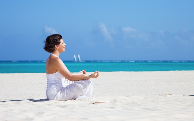 meditação de mulher feliz em pose de lótus na praia