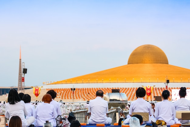 Meditação dos povos e da monge em Wat Dhammakaya na frente do pagode de Dhammakaya em Tailândia.