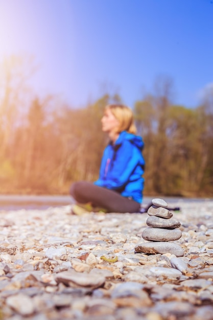 Meditação e relaxamento Cairn em primeiro plano mulher meditando no fundo desfocado Aproveitando o sol da manhã