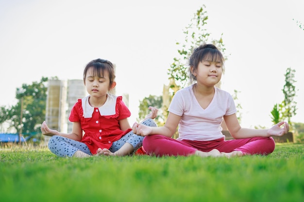 Meditação infantil com pose de ioga na grama verde Atividade para saúde e bem-estar das crianças