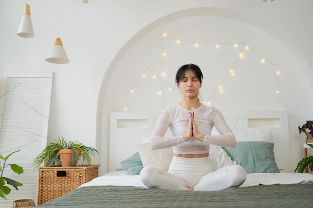 Meditação mindfulness de ioga jovem mulher saudável praticando ioga no quarto em casa mulher sentada em