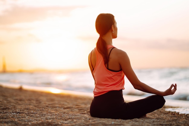 Meditação Mulher jovem fazendo ioga perto do oceano descalça Calma e equilíbrio estilo de vida saudável