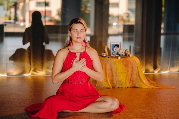 Meditación y concentración una mujer con un vestido rojo sentada en el suelo con los ojos cerrados está practicando medicina en el interior Paz y relajación