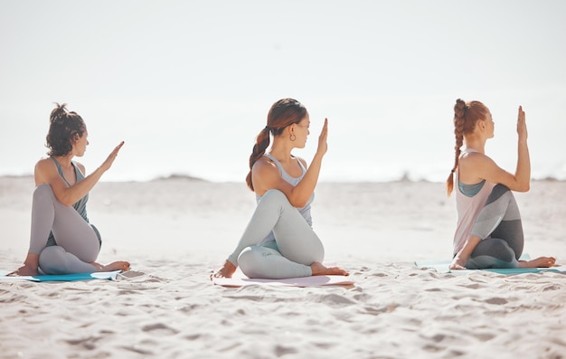 Meditación en grupo de yoga y salud zen en una playa con mujeres entrenando y meditando juntas Amigos atléticos ejercitan la postura de práctica y equilibran la pose de yoga con energía pacífica zen en la naturaleza