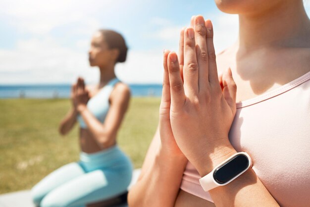 Foto meditación de manos y reloj inteligente de amigos que hacen yoga en el campo para la salud física y la paz con equilibrio entrenamiento zen y seguimiento cardiovascular de guardia con mujeres en posturas de yoga uniéndose y meditando