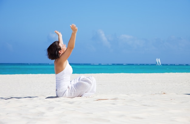 meditación de mujer feliz en posición de loto en la playa