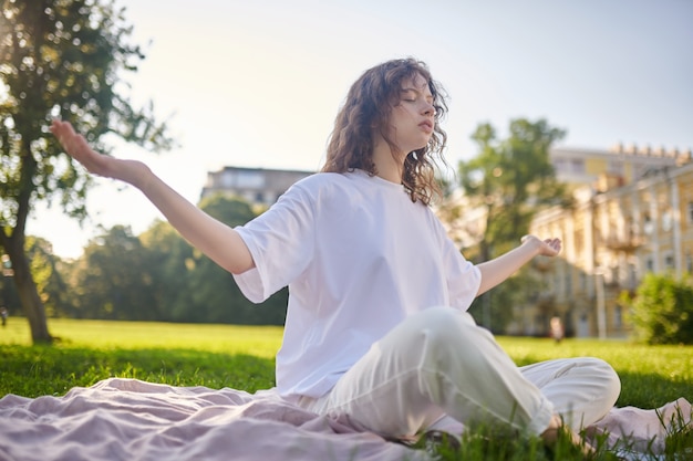 Meditación. Una niña sentada en una pose de loto y meditando en el parque.