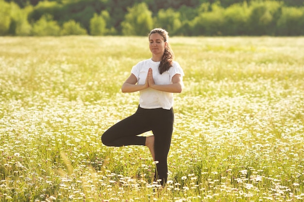 Meditación y yoga en el campo de manzanilla natural. Mujer joven en armonía con la naturaleza sintiéndose libre