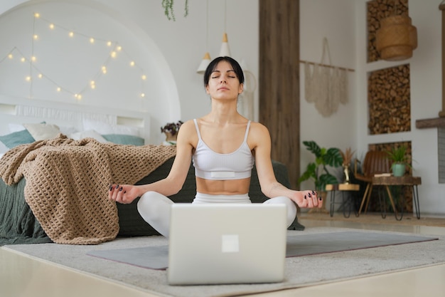 Meditación de yoga en línea mujer practicando yoga con lecciones en línea en la computadora portátil en casa mujer