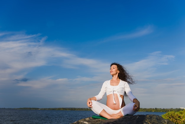 Meditando a mulher grávida ao ar livre.