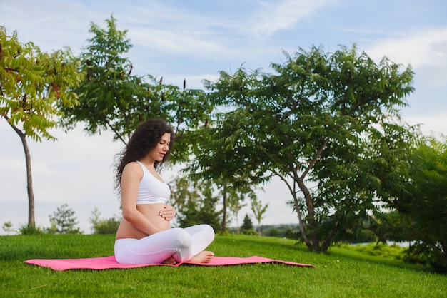 Meditando a mulher grávida no parque.