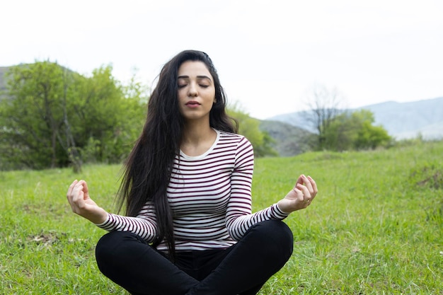 Meditando a mulher sentada na grama verde