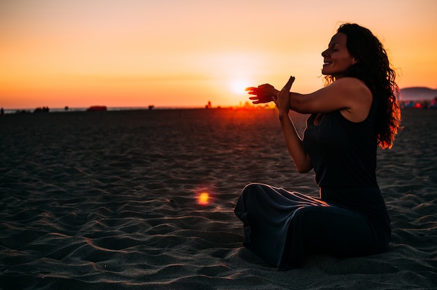Meditation der jungen Frau auf Sonnenuntergangstrand
