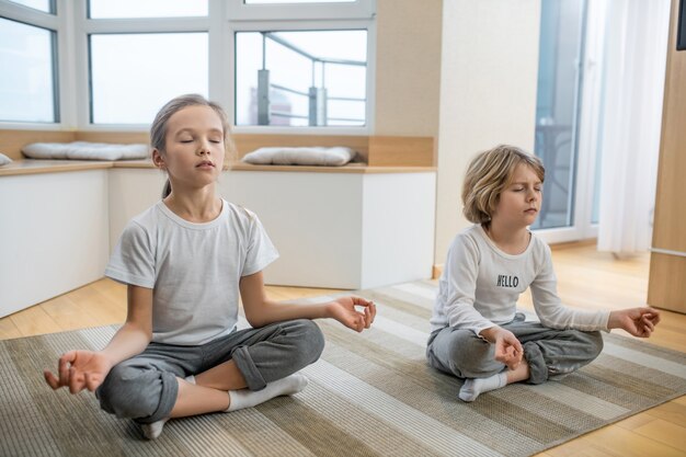 Meditation. Kinder machen zu Hause zusammen Yoga und sitzen in Meditation