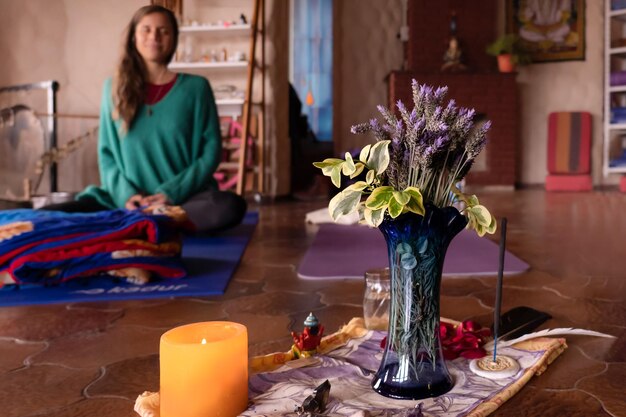 Meditationsaltar mit Lavendelblumen und Weihrauch Hintergrund verschwommen mit einer jungen Frau, die meditiert