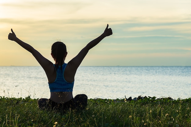 Meditationsyoga-Lebensstil-Frauenschattenbild auf dem Seesonnenuntergang, entspannen sich vital. Gesundes Konzept