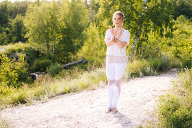 Foto meditative meditierende dame, die mit geschlossenen augen auf der natur steht und gekreuzte hände in yoga-mudra hält
