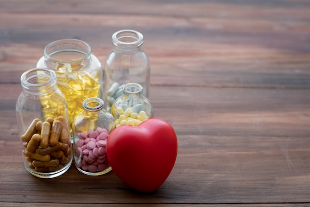 Foto medizin in der flasche und im herzen auf hölzerner tabelle.