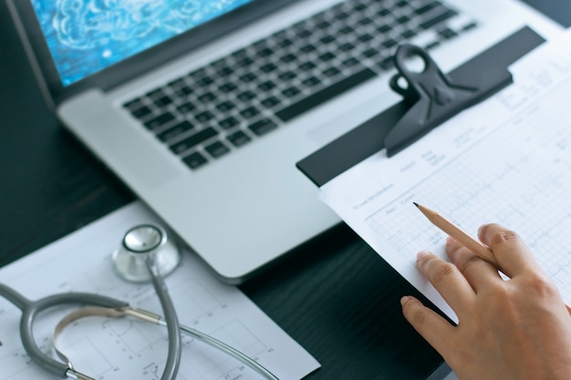 Medizindoktor und -stethoskop auf dem Berichtsdiagramm, arbeitend mit Laptop-Computer auf Krankenhaus.