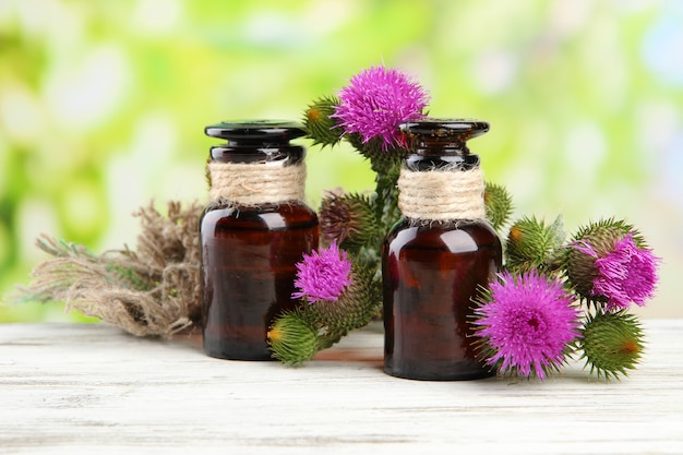 Medizinflaschen mit Distelblumen auf Natur