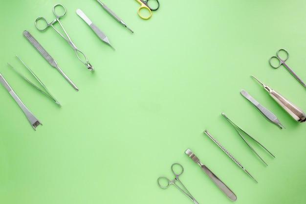 Medizinische Ausrüstungen einschließlich chirurgischer Instrumente auf einem grünen Hintergrund. Draufsicht, Spase kopieren