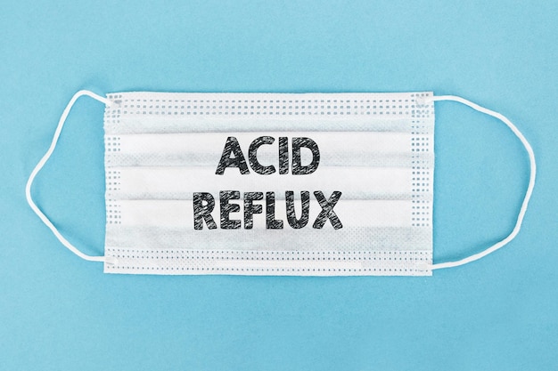 Medizinische Gesichtsmaske mit ACID REFLUX-Text auf blauem Hintergrund