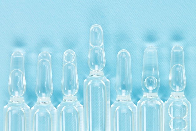 Medizinische Glasfläschchen oder Medizinampullen mit Flüssigkeit an der blauen Wand