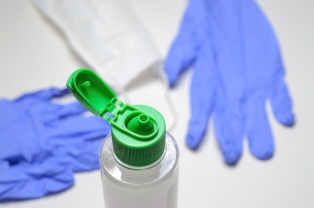 Foto medizinische handschuhe und glas mit desinfektionsmittel auf weiß