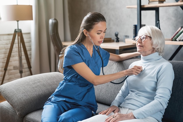 Medizinische Hilfe Asiatische Krankenschwester mit Stethoskop für ältere Frauen im Innenbereich