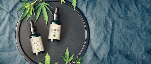 Foto medizinische marihuana- und cannabisprodukte cbd-öl, hanfblätter auf dunklem tisch