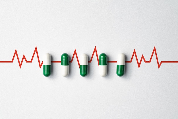Medizinische Pillen auf weißem Hintergrund mit Kopierraum und Herzfrequenz-Symbol