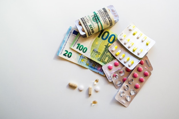 Medizinische Tabletten und Kapseln. Banknoten als Kosten für die Herstellung von Arzneimitteln