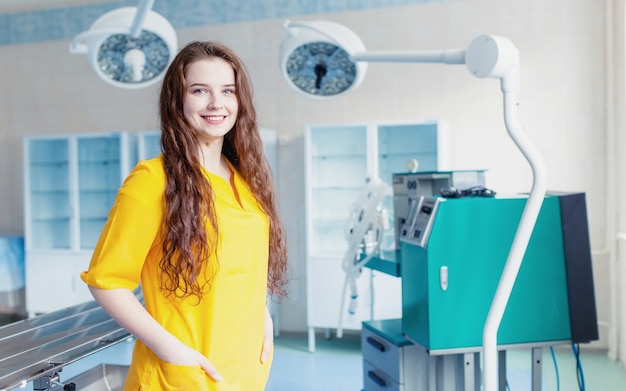 Medizinische Technologie. Schönes Mädchendoktorlächeln. helles Porträt. Konzept des Arzthintergrundes in gelber Form im Operationssaal. Ausrüstung